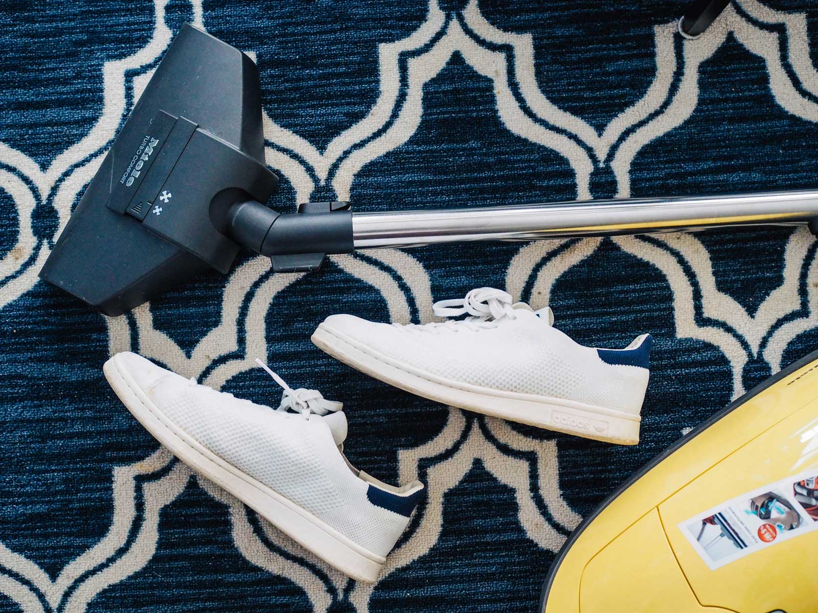 Shoes on carpet removed while vacuuming the carpet